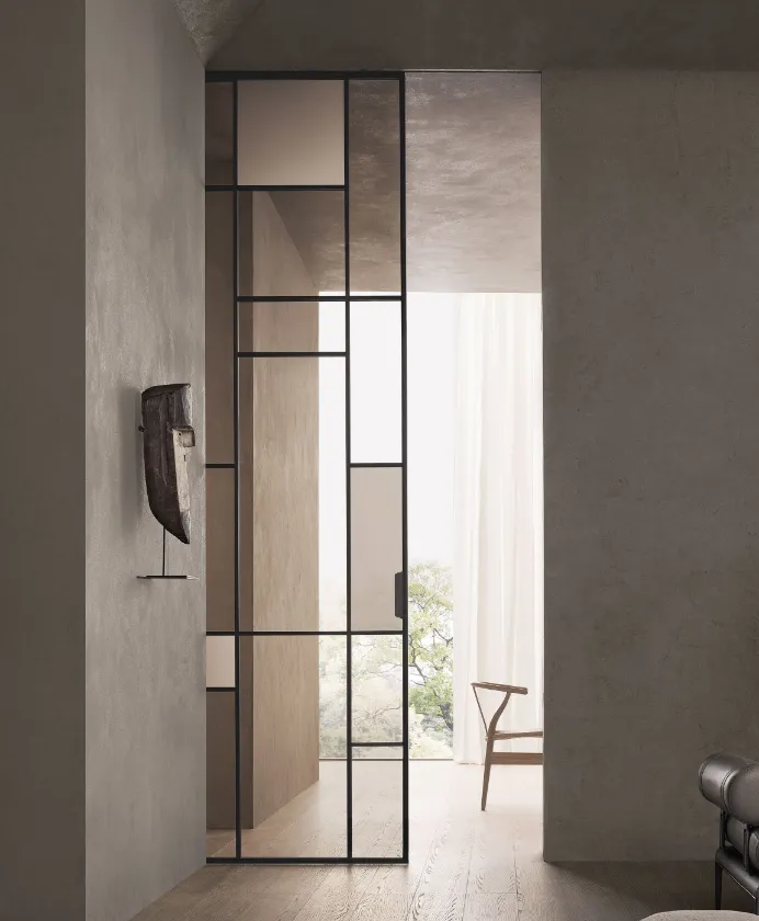 Black-framed glass pivot door between two rooms